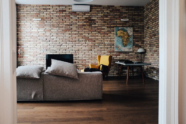 Hoe ziet jouw DroomHome er uit? Industriële woonstijl: Bakstenen muur in de woonkamer met een grote stoffen loungebank (Foto Pixabay.com, StockSnap  op DroomHome.nl)