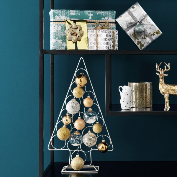 Kerst 2018 – Kerstdecoratie met gouden kerstballen in de kerstboom – kerstornamenten, rendieren en kerstcadeaus in een open zwarte stalen kast (Foto Bol.com  op DroomHome.nl)